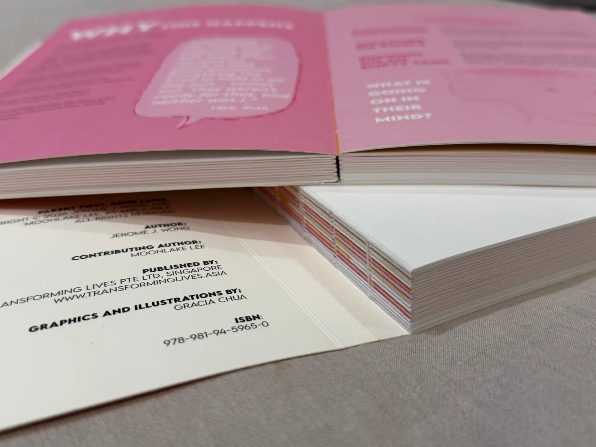 Swiss binding — book lying flat open showing the pink interior pages and exposed spine